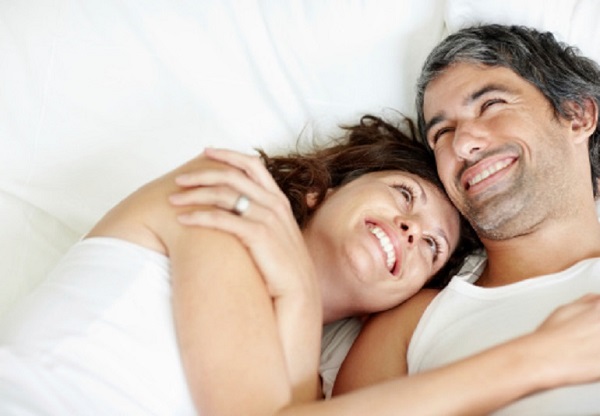 Cosy mature couple lying in bed smiling